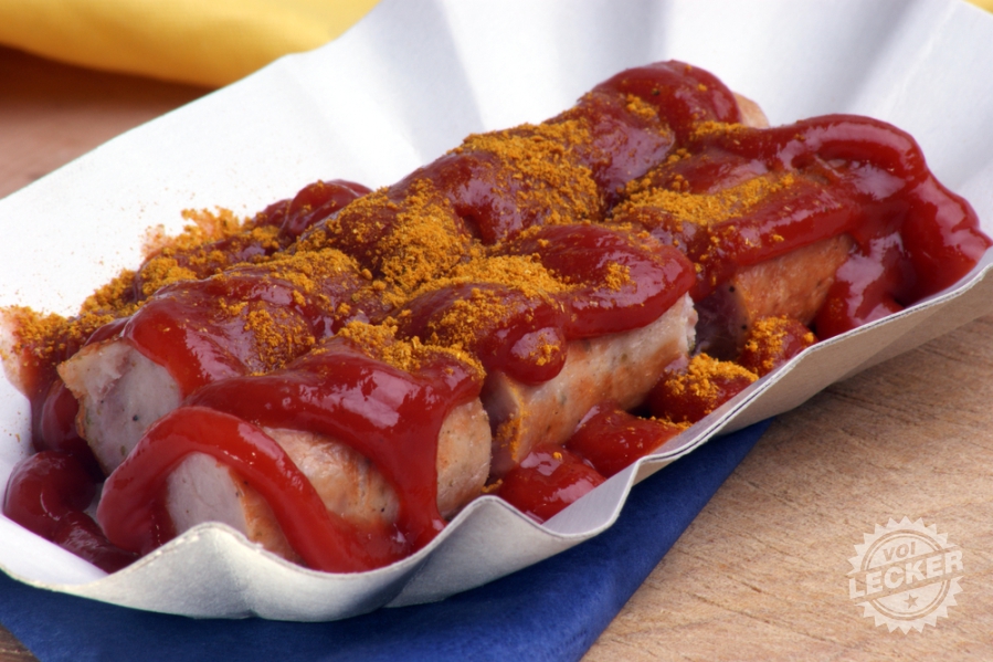 Currywurst mit Currysauce und Currypulver auf Pappteller
