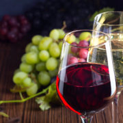 Glasses with red and white wine with grapes on wooden background Qualitätsweine