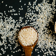 Organic natural sesame seeds wooden spoon. toasted sesame seeds. Raw, whole, unprocessed. Natural light. Selective focus. Close up on a black background. Top view, flat lay. copy space for text. Sesam